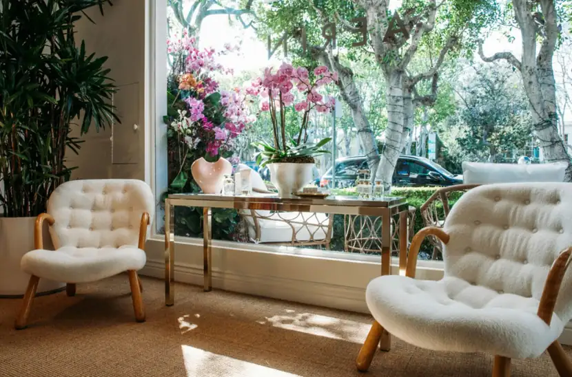 Sunlit shop interior with cream bouclé chairs and orchids at the window