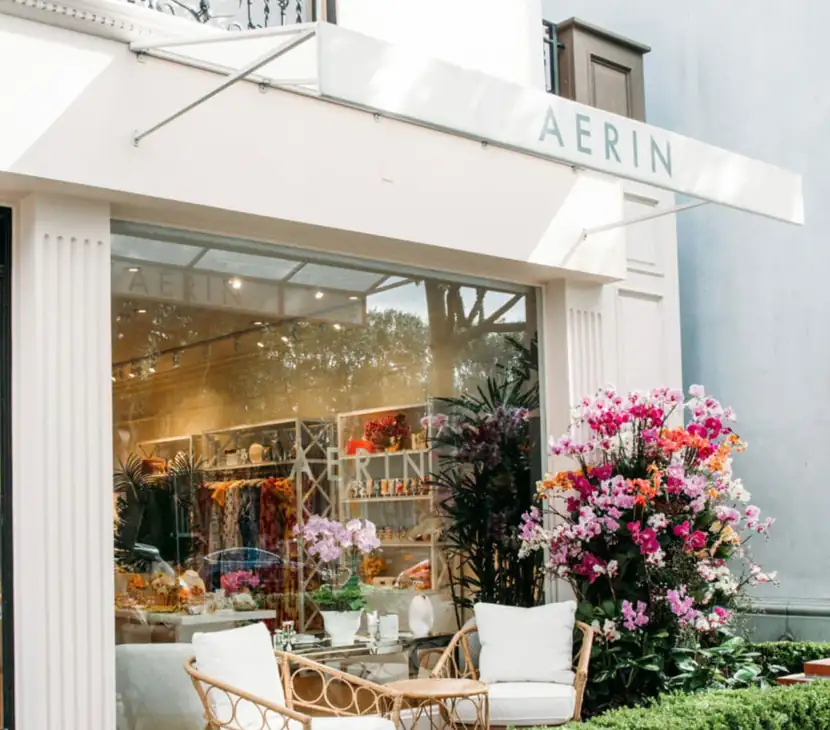 Aerin storefront with a white awning, blossoms and rattan seating