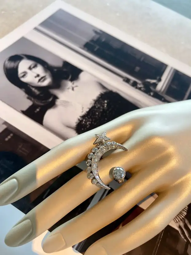 A diamond cuff modelled on a hand beside a black-and-white archival portrait