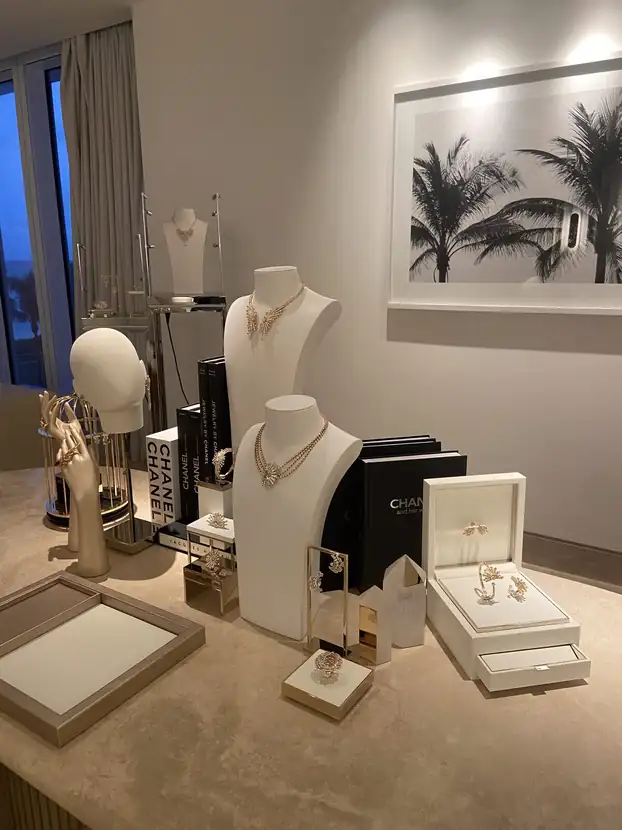 Fine jewelry displayed on white busts and trays in a light-filled suite
