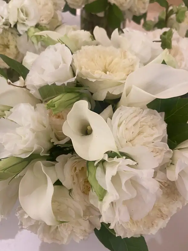 White calla lilies, roses and carnations arranged in a low centerpiece