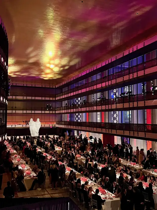Guests seated at long banquet tables in a multi-tiered ballroom with projected lighting