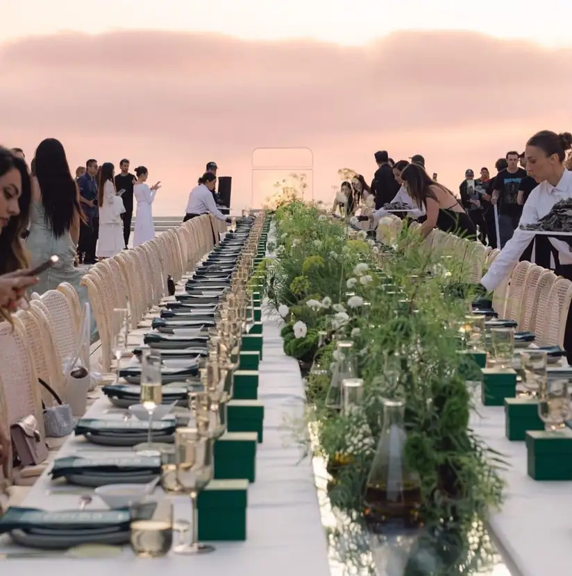 Guests gathered along a candlelit banquet table at dusk