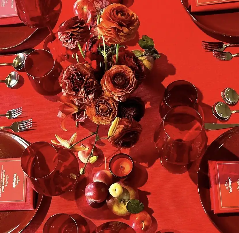 Overhead view of a scarlet tablescape layered with red roses, apples and glassware