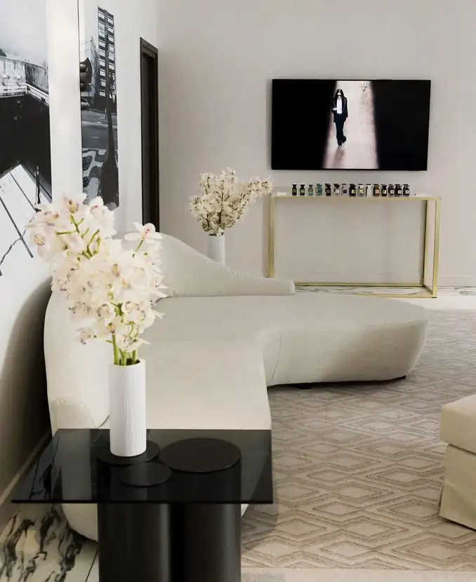 Curved cream sofa and black marble table styled with white orchids