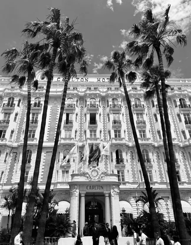 Black-and-white photograph of the Carlton hotel façade framed by palm trees