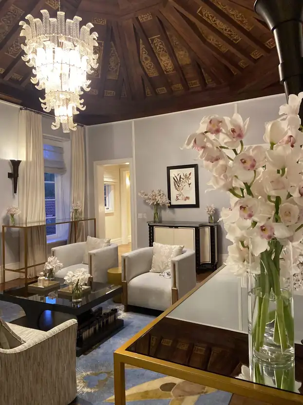 Hotel suite sitting room with a chandelier, white orchids and mirrored consoles