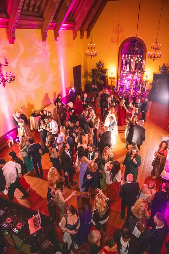 Guests filling a dance floor in a grand room lit in magenta