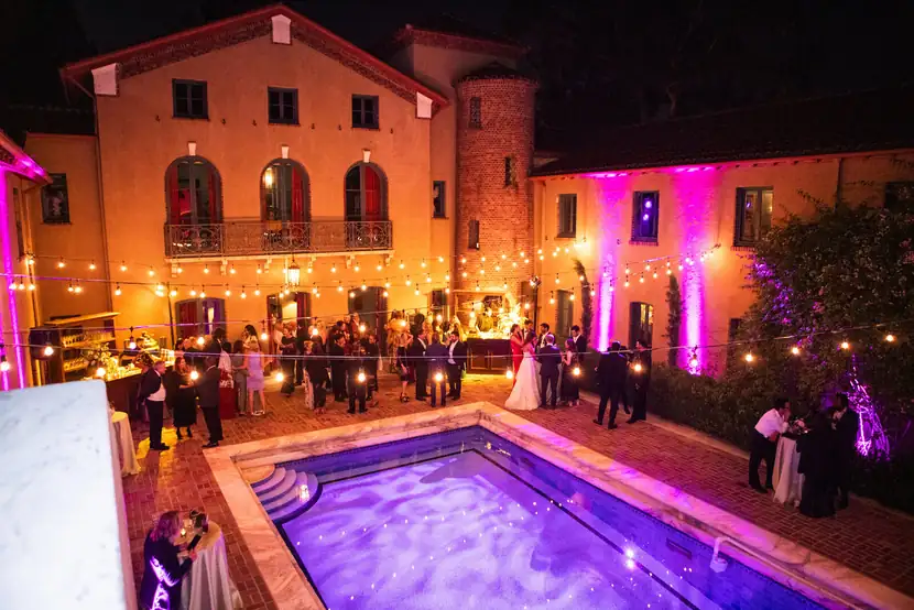 The pool courtyard lit in violet as the reception continues after dark